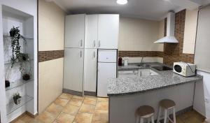 a kitchen with white cabinets and a counter with stools at Velazquez in Lora del Río