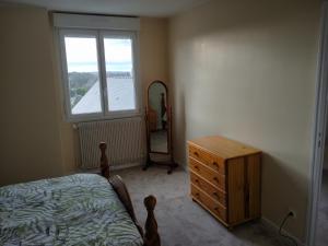 a bedroom with a bed and a dresser and a window at La Petite Maison Celtique in Saint-Nicolas-du-Pélem