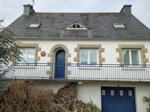 a house with a blue door and a balcony at La Petite Maison Celtique in Saint-Nicolas-du-Pélem
