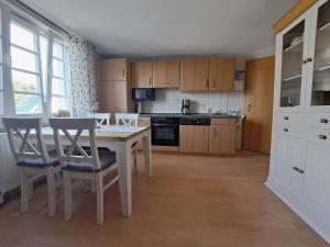 une cuisine avec une table et des chaises en bois et une table et une cuisine avec dans l'établissement Ferienwohnung Fortuna II, à Thiessow
