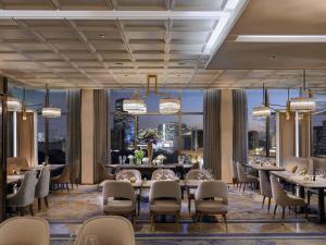 a dining room with tables and chairs and large windows at VIE Hotel Bangkok - MGallery Collection in Bangkok