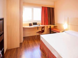 una camera da letto con un letto e una scrivania con un computer portatile di ibis Uberlandia a Uberlândia