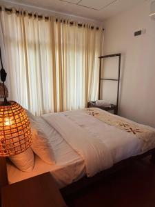 een slaapkamer met een bed met een lamp en een raam bij Red Heritage in Dikwella