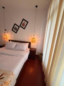 een slaapkamer met een bed, 2 lampen en een raam bij Red Heritage in Dikwella +11 foto's
