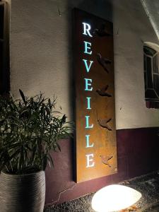 een bord aan de zijkant van een gebouw met een potplant bij B&B Reveille in Kleve