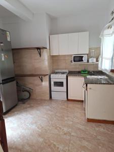 a kitchen with white cabinets and white appliances at Departamentos MDA MIC in Mar de Ajó