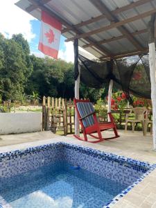 a red chair sitting next to a swimming pool at Canada House Queen bed in 2nd floor dbl sofa bed in 1st floor BBQ Private pool, river in Jarabacoa