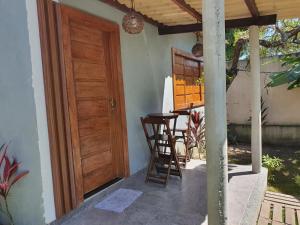 a porch with a wooden door and a table and chairs at Bangalô em uma área próxima a praia e centro in Porto Seguro