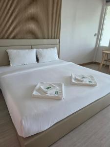 a white bed with two towels on top of it at Madee House - มาดีเฮ้าส์ in Ban Ao Yang