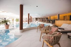 una hall con piscina, tavoli e sedie di Hotel Hohenwart a Scena