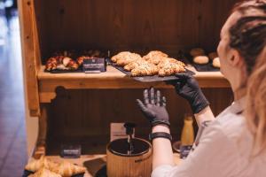 Una donna tiene in mano un vassoio di dolci. di Hotel Hohenwart a Scena