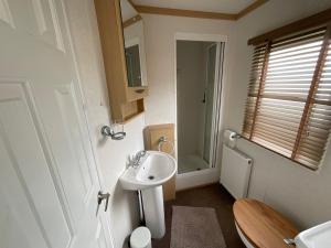 a small bathroom with a sink and a toilet at Seaside Sanctuary in Hemsby +12 photos
