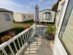 a balcony with a table and chairs and an umbrella at Seaside Sanctuary in Hemsby