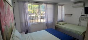 a small room with two beds and a window at Casa La Fe in Cartagena de Indias