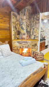 a bed in a room with a stone wall at Pousada Portal do Céu in Visconde De Maua