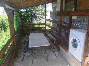 a table and chairs on a porch with a washing machine at Bungalow citron in Petit-Bourg