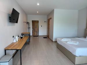 a bedroom with a bed and a desk and a tv at Madee House - มาดีเฮ้าส์ in Ban Ao Yang