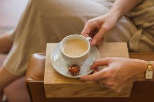 a woman holding a cup of coffee on a table at Story Haus in Stellenbosch