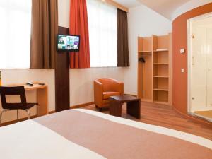 a hotel room with a bed and a desk and a tv at ibis Karlsruhe Hauptbahnhof in Karlsruhe