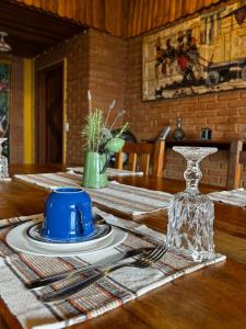 a table with a blue cup and plates on it at Pousada Portal do Céu in Visconde De Maua