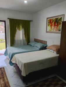 two beds in a bedroom with green curtains at Suite do lar in Timbó