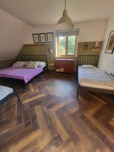 a room with three beds and a wooden floor at Chata Kolmanovci in Oščadnica