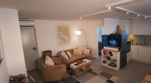 a living room with a couch and a tv at Green Garden , HOMEANDSAIL in Jezera