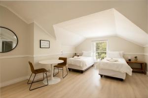 een slaapkamer met 2 bedden, een tafel en een spiegel bij Story Haus in Stellenbosch