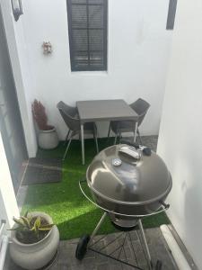 a grill on a patio with a table and chairs at The College Suite, Mill Park in Gqeberha +2 photos