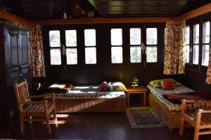 a bedroom with a bed and a table and windows at Nalze Khar in Raogi