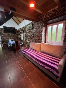 a couch in a room with a stone wall at Casa Duque in Santana with AC and heating in Santana