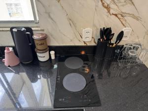 un piano di lavoro con una stufa e alcuni utensili di Apartamento Central Próximo da praça Tiradentes e Hospital a Teófilo Otoni