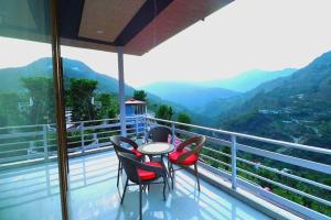 a table and chairs on a balcony with mountains at The Himalayan Majesty Hotel in Chopta