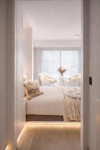 a white bedroom with a bed and a window at Studio Fifty9 in Knokke-Heist
