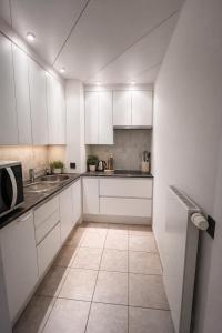 a white kitchen with white cabinets and a tile floor at Studio Fifty9 in Knokke-Heist