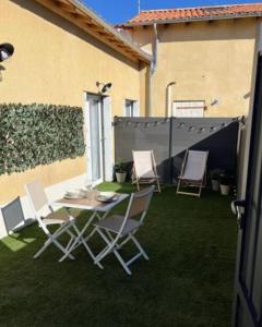 a patio with chairs and a table on the grass at Slow studio, Les Clés de l'Espoir, proche Poitiers in Nieuil-lʼEspoir