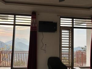 a room with a television and a balcony with windows at Revanta Home Stay in Anandpur Sāhib