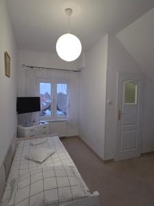 una camera da letto bianca con un letto e una finestra di Biesiadny Dworek a Szpegawa