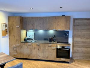 una cucina con mobili in legno, un lavello e una stufa di Appartement Bergsicht a Leogang