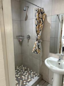 eine Dusche mit Waschbecken und Duschvorhang in der Unterkunft Monica's Guesthouse in Welkom + 5 Fotos