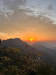 a sunset with the sun setting on a mountain at Revanta Home Stay in Anandpur Sāhib
