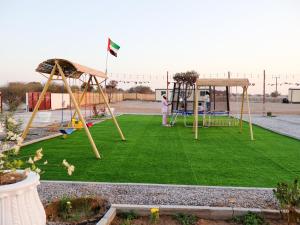 a person standing in a playground with two swings at Alharamil Retreat in Ras al Khaimah