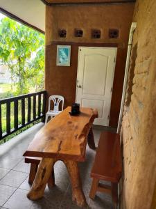 a wooden table and bench on a balcony with a door at Earth House HomeStay Bangjo in Ban Pak Lak +9 photos