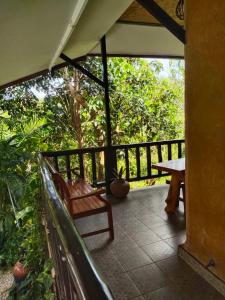 a porch with a wooden bench and a table at Earth House HomeStay Bangjo in Ban Pak Lak