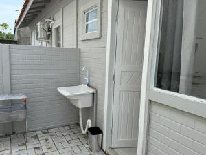a white bathroom with a sink and a window at Loft novo e bem localizado in Biguaçu +25 photos