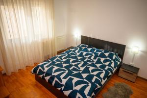 a bedroom with a bed with a blue and white comforter at House Dey in Făgăraş