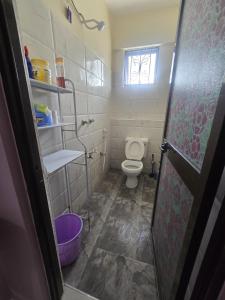een kleine badkamer met een toilet en een raam bij Flynn Stays in Bamburi +7 foto's