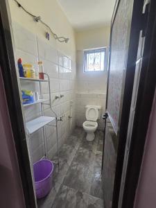 een kleine badkamer met een toilet en een raam bij Flynn Stays in Bamburi
