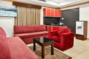 een woonkamer met rode meubels en een keuken bij Al Thill Hotel in Mekka