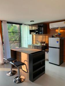 een keuken met een aanrecht met 2 krukken en een koelkast bij Mae on country home in Ban On Luai